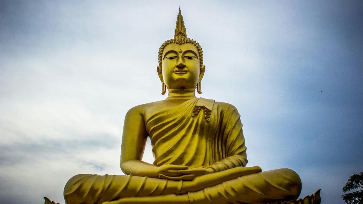 A majestic golden Buddha statue against a serene blue sky, symbolizing peace and spirituality.