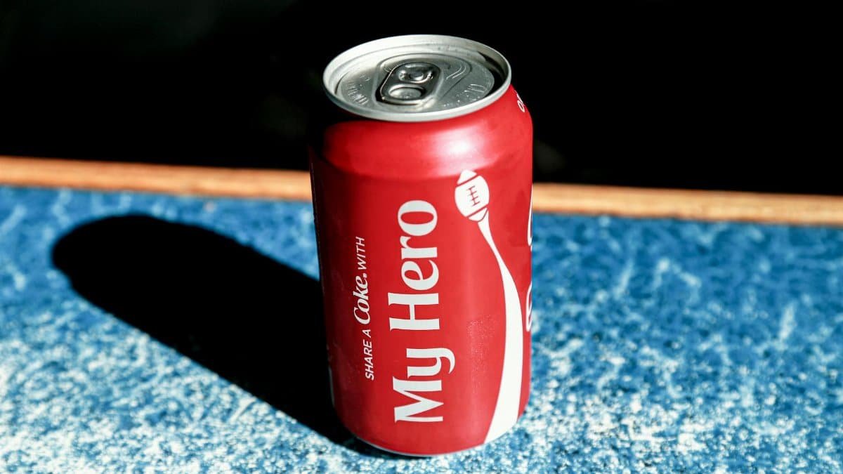 From above of red metal can with refreshing fizzing coke placed on table in cafe