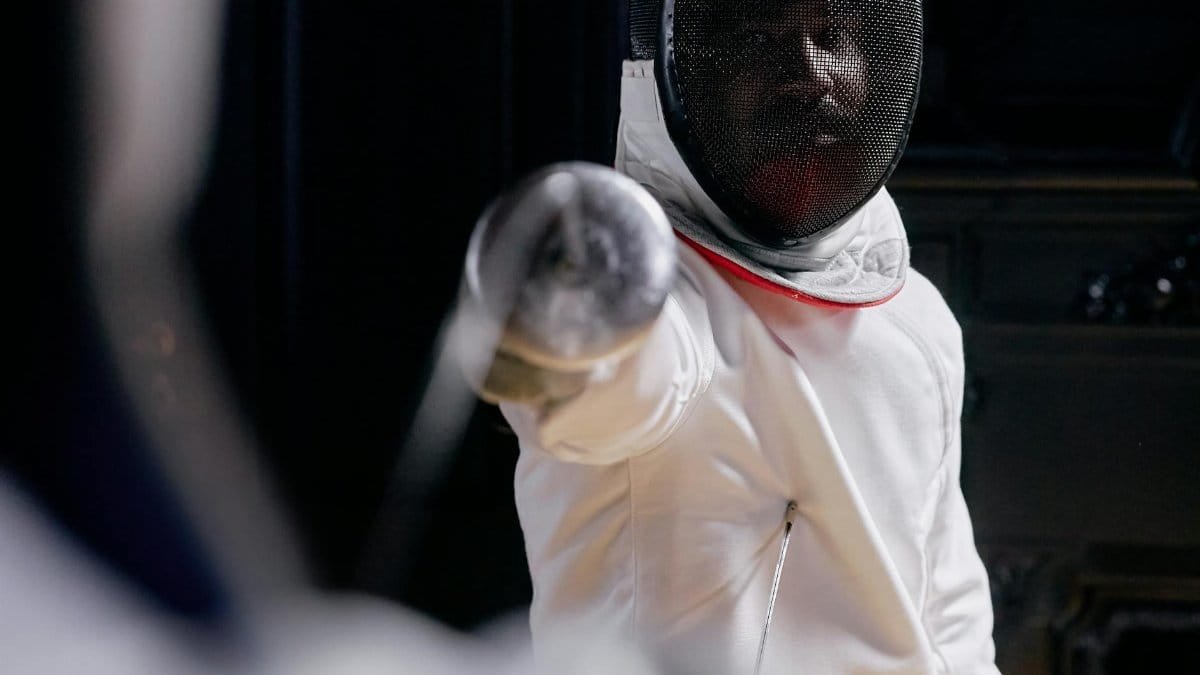 Close-up of a fencer in action, ready to strike during an indoor competition.