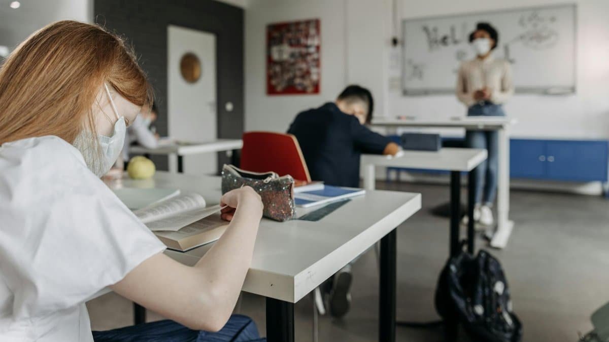 Students wearing masks while studying in a classroom setting during a lesson.