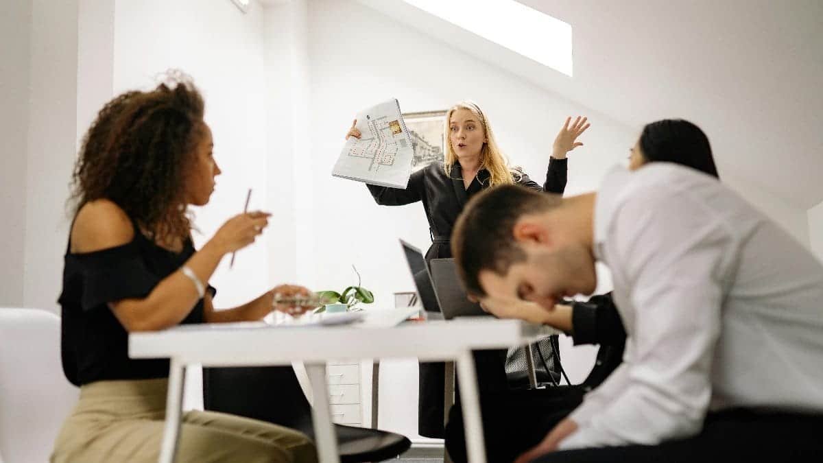 Team experiencing stress during a heated office meeting. Diverse colleagues engage in emotional discussion indoors.