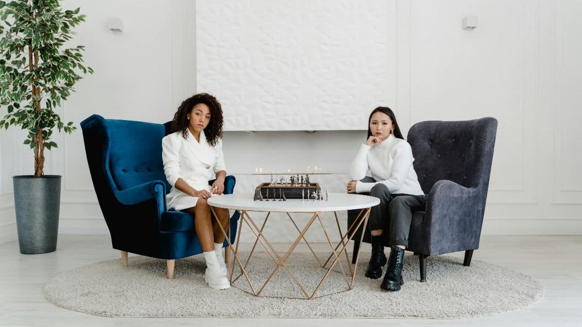 Two women in a modern room playing chess, showcasing strategic focus. via Pexels