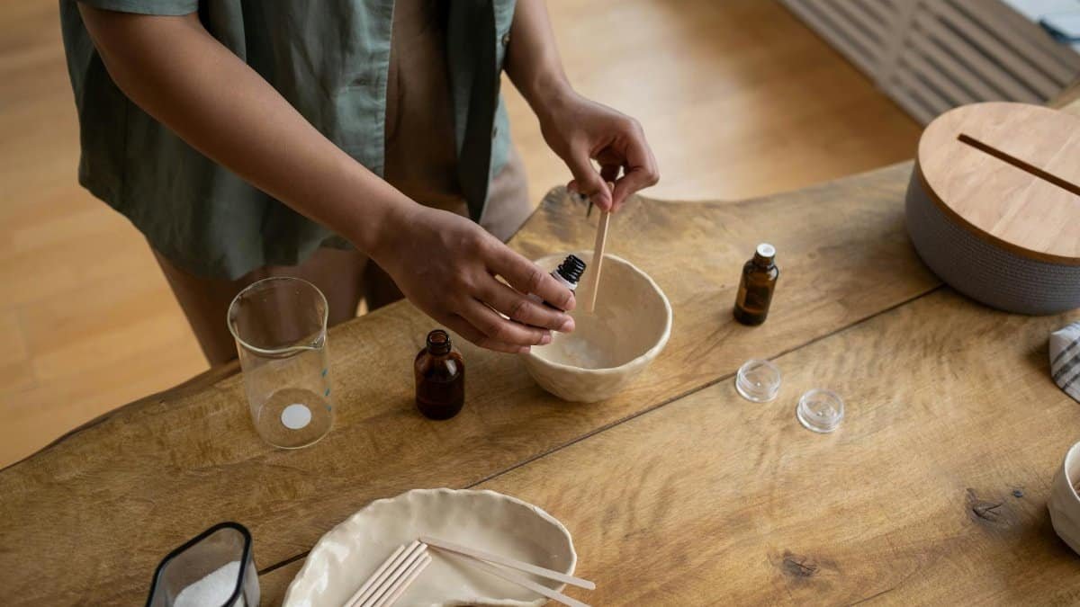 Close-up of hands making homemade lip balm in a cozy indoor setting.