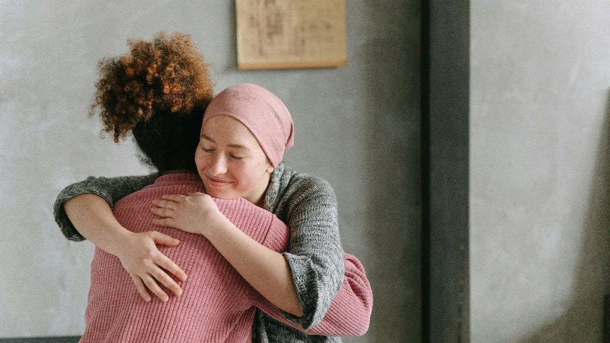 Two women embracing each other with warmth and love, symbolizing support and care indoors.