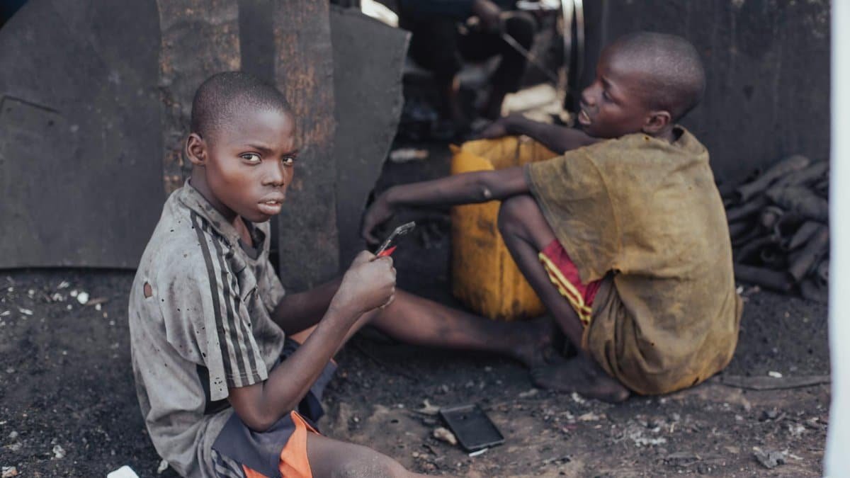 Two children working with tools in a rustic environment, illustrating child labor and hardships.