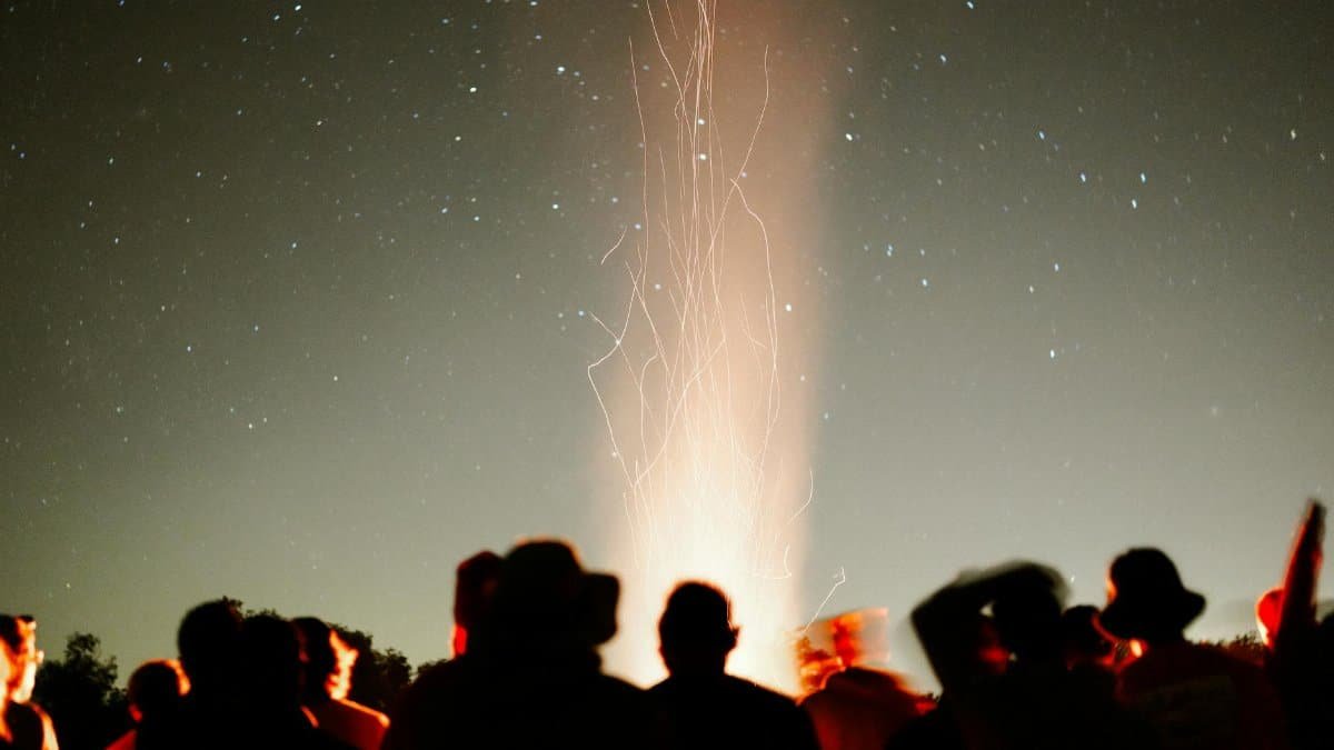 A group of people enjoying a campfire under a starlit sky, creating a warm and social atmosphere.