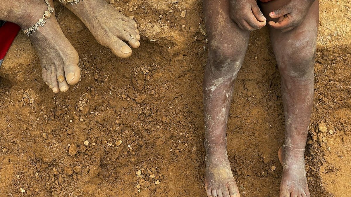 Close-up of bare feet on brown soil, highlighting rural lifestyle in Rasulpur, India.