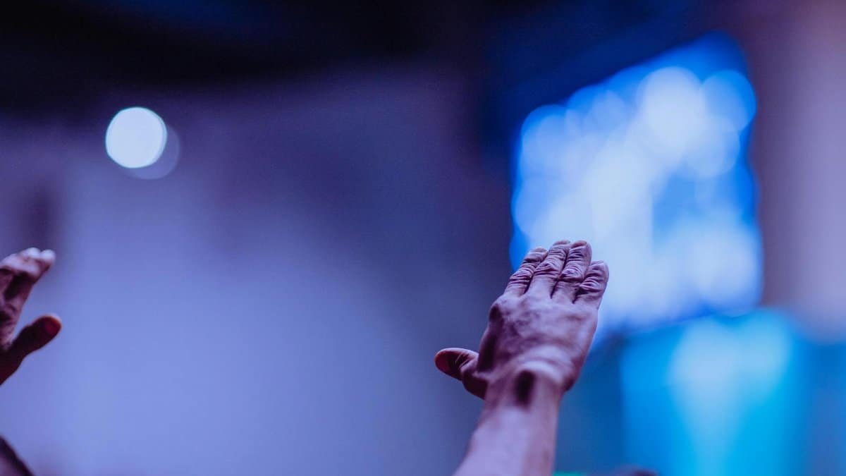 A close-up of hands raised during a church worship service, emphasizing community and praise.