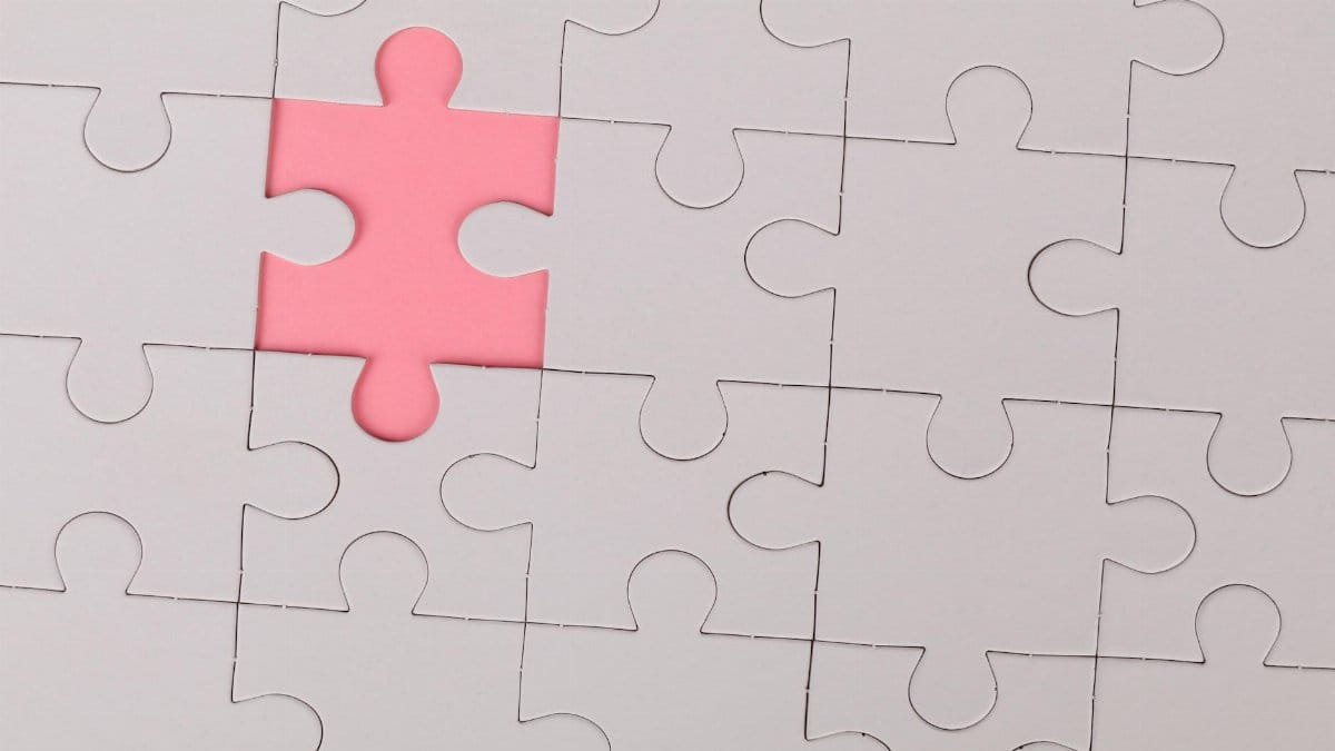 Close-up of an unfinished puzzle with a pink missing piece, highlighting emptiness.