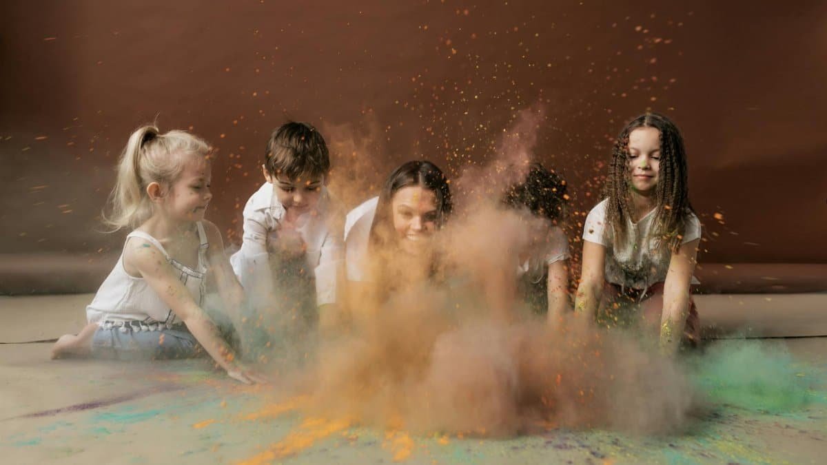 Cheerful children playing with vibrant colored powder, celebrating Holi indoors.