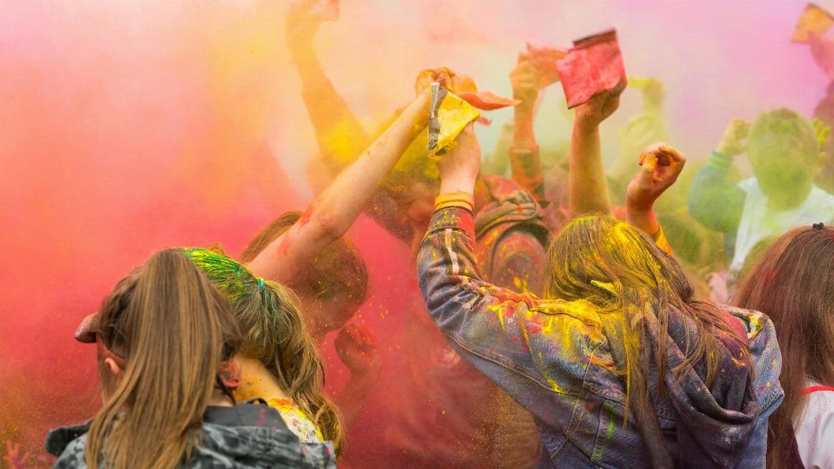 People enjoying a lively festival with colorful powder in the air, symbolizing joy and unity.