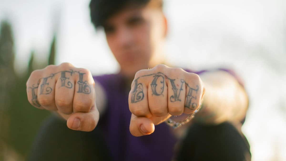 Close-up of tattooed fists showing 'Love Hate' outdoors, emphasizing self-expression.