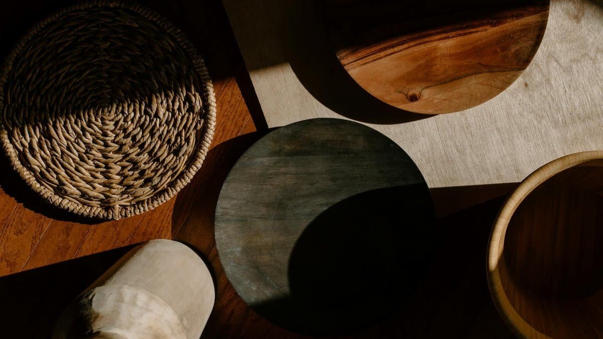 A flat lay of wooden kitchen utensils and woven materials in warm natural lighting, showcasing minimalist design.