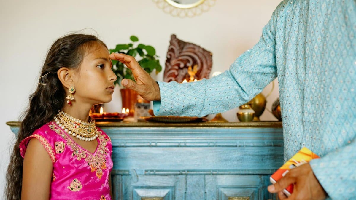A young girl undergoes a traditional Indian ritual indoors, highlighting cultural and religious practices.