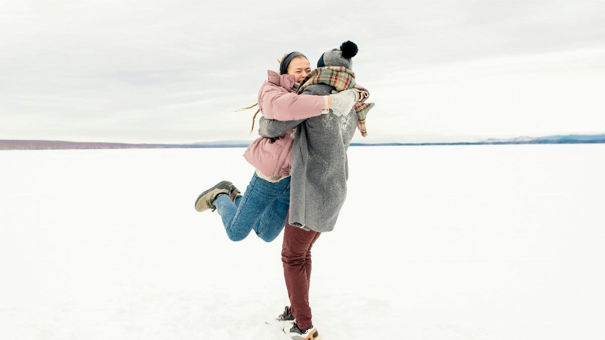 Joyful couple embracing in a winter wonderland, capturing fun and happiness in the snow.
