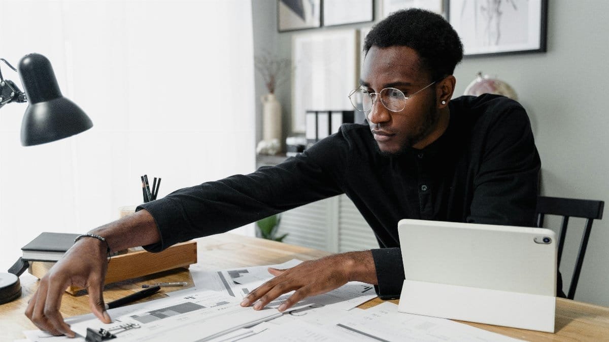 Business professional working at desk reviewing financial documents with digital tablet.