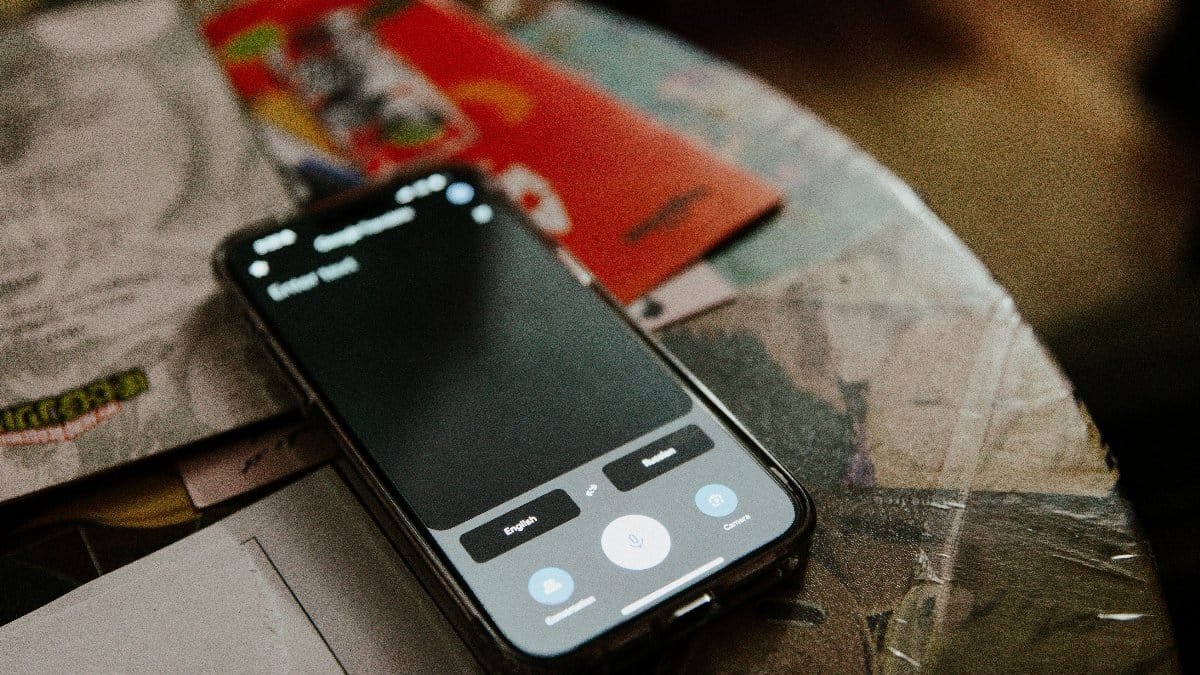 Modern smartphone on cluttered desk with books and notes reflecting daily life.