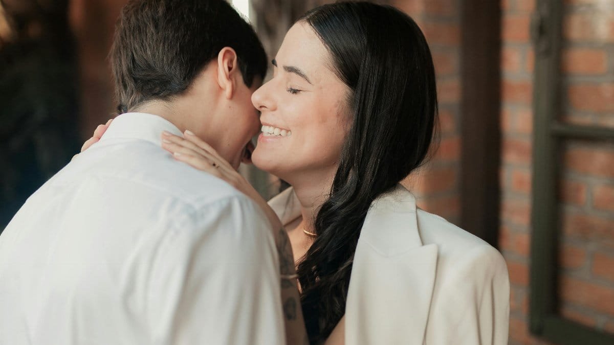 A romantic couple embraces lovingly against a brick wall backdrop. via Pexels