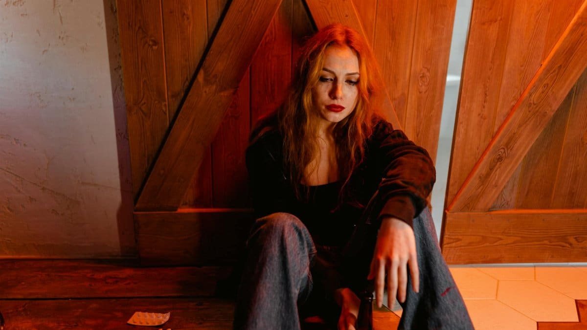 Emotional woman sitting indoors depicts solitude and contemplation.