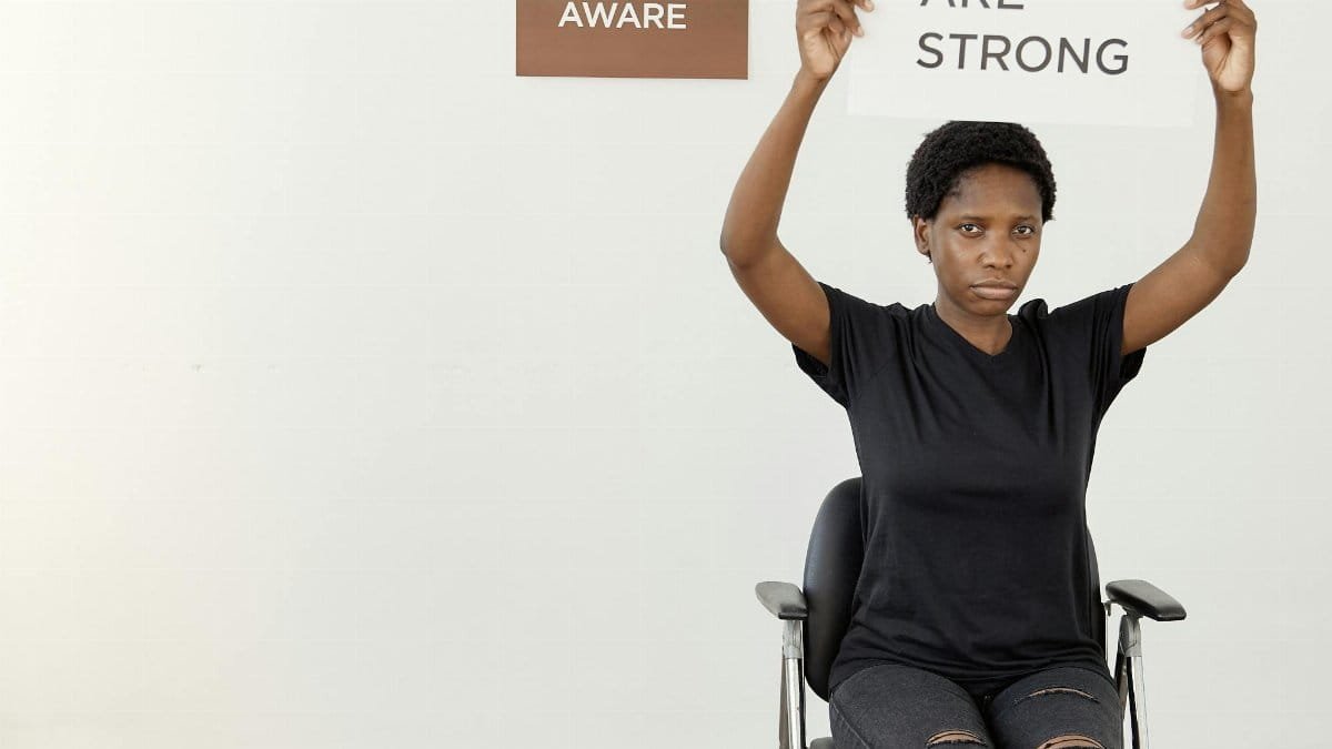 Black woman holding a sign with an empowering message, advocating awareness and strength.