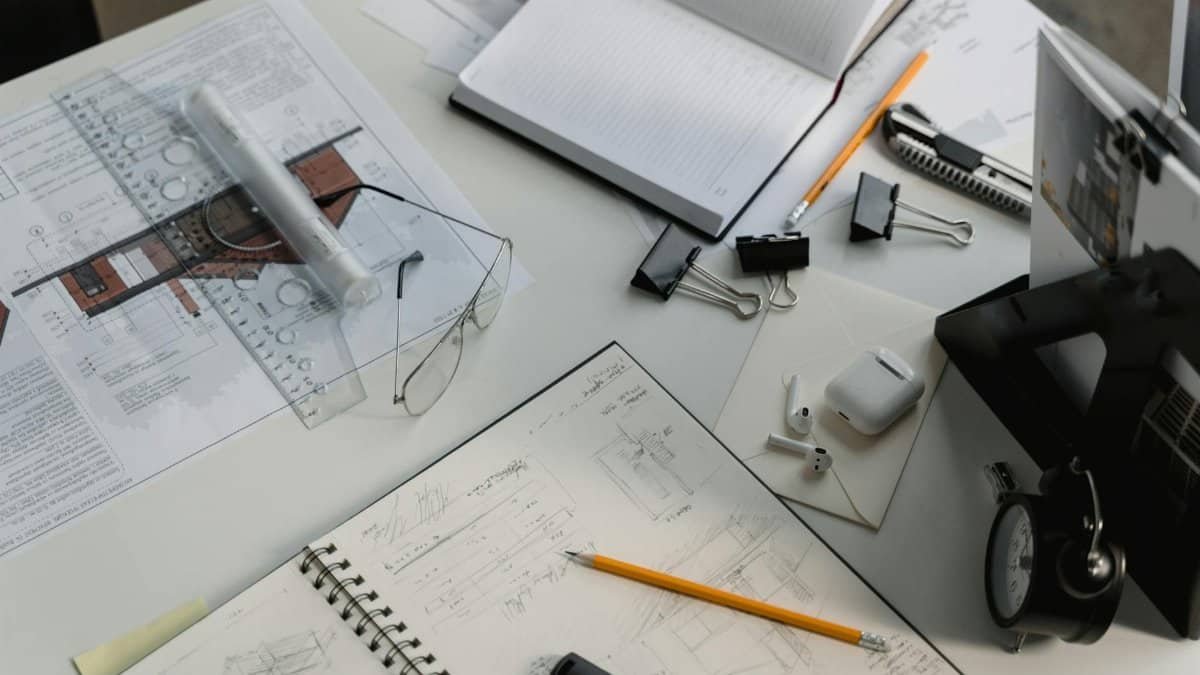 A busy architectural workspace featuring blueprints, sketches, and drafting tools.
