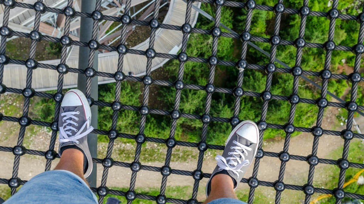 A unique view of a forest from a rope bridge with a focus on sneakers and net. Perfect for adventure and travel themes.