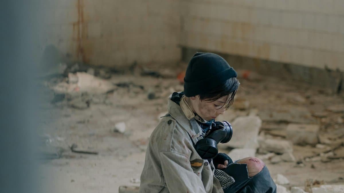 A young person in survival gear explores a decaying, abandoned building interior.