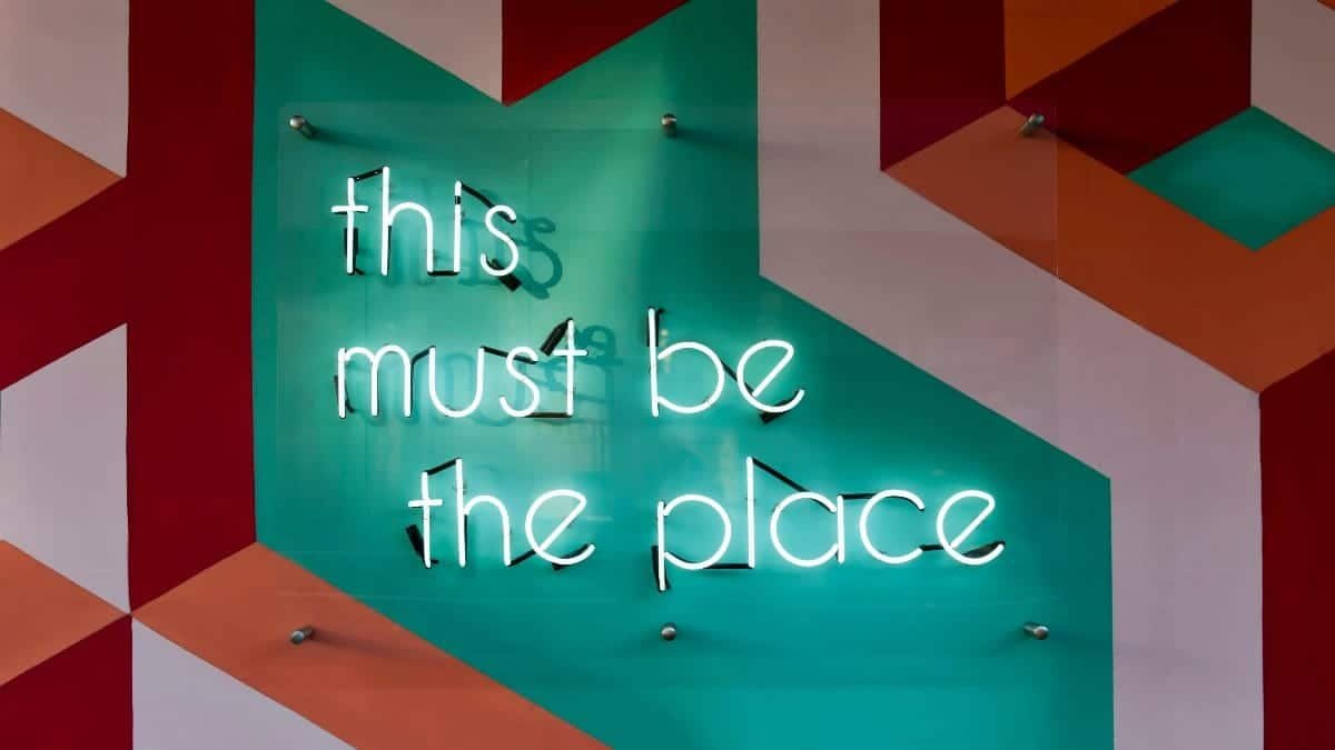 Colorful geometric wall featuring a glowing neon sign with an inspirational quote.