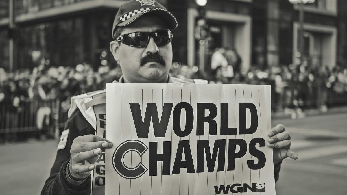 A man holds a 'World Champs' sign during a celebratory parade. Monochrome image.