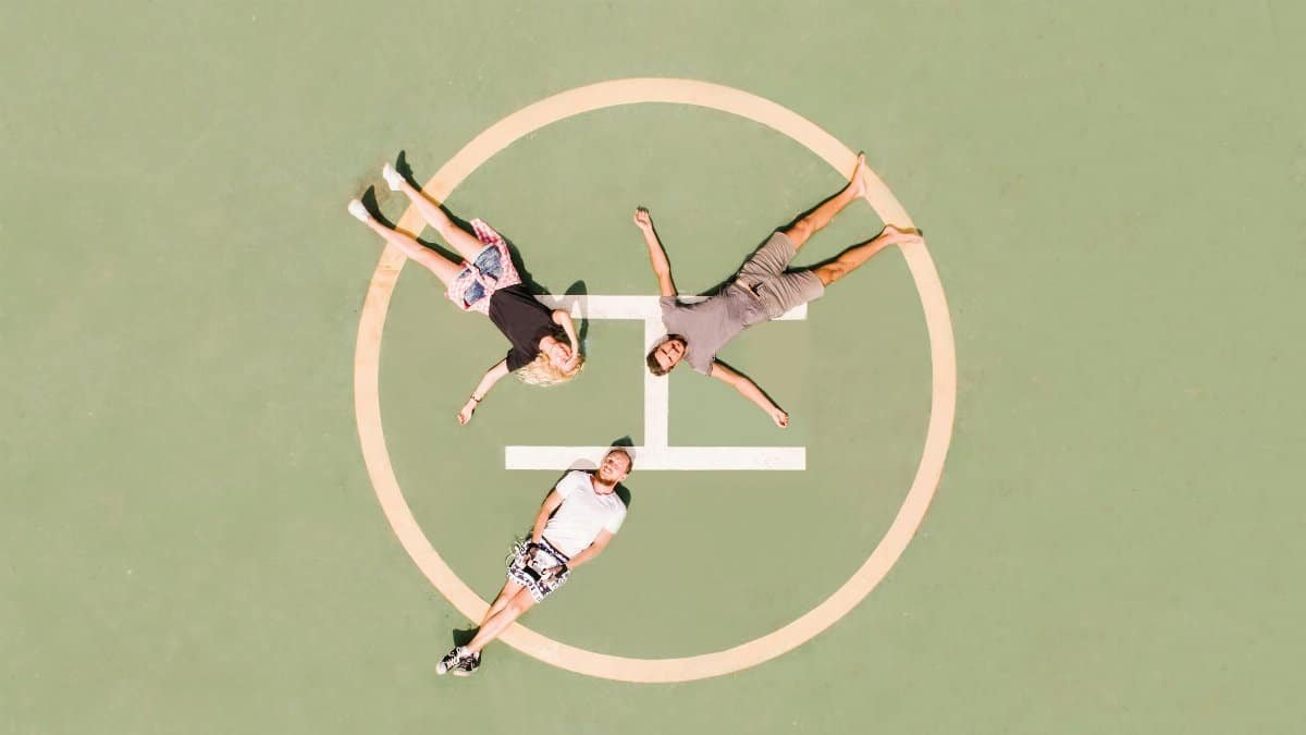 High-angle aerial shot of three people lying on a helipad, enjoying a sunny day. via Pexels