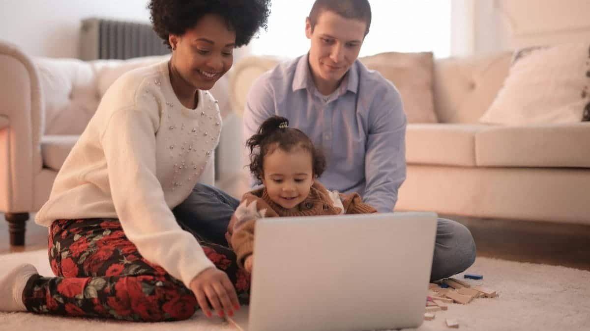 A family enjoying quality time together using a laptop in a warm and cozy living room.