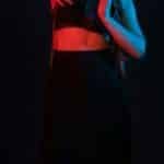 A female dancer poses gracefully under dramatic red and blue stage lighting. via Pexels
