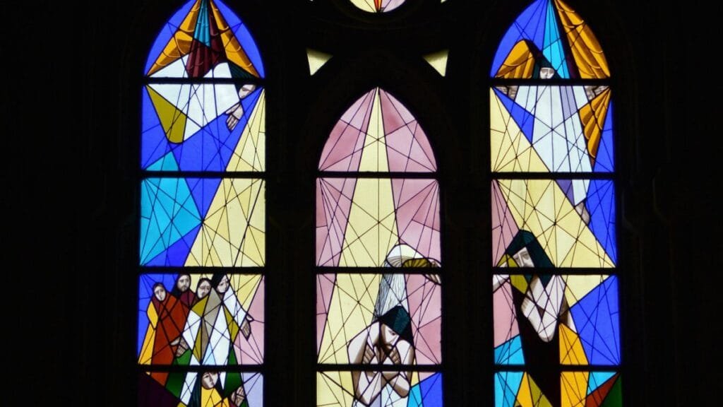 Colorful stained glass window in a church depicting religious scenes. via Pexels