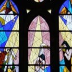 Colorful stained glass window in a church depicting religious scenes. via Pexels