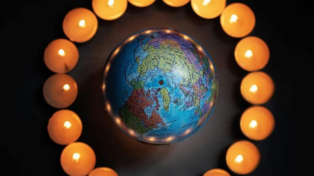 A globe encircled by lit candles symbolizes global unity and peace. via Pexels