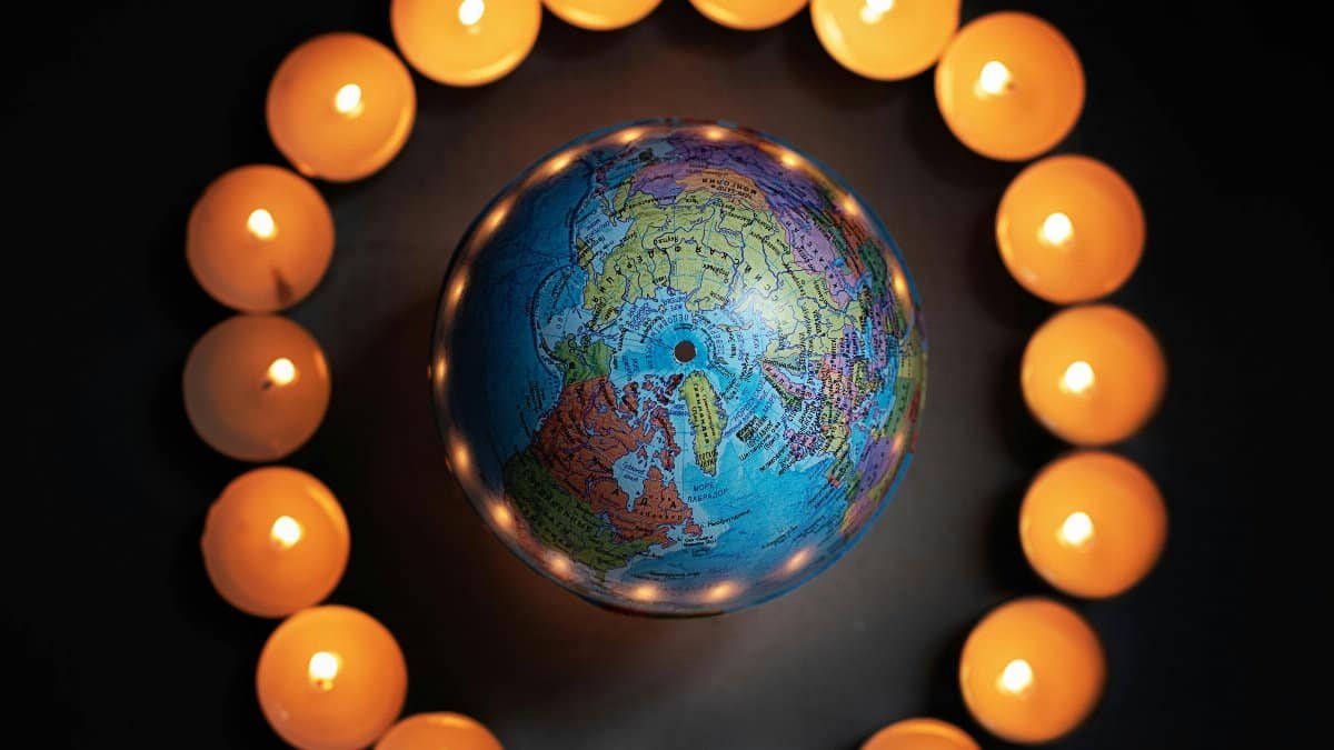 A globe encircled by lit candles symbolizes global unity and peace. via Pexels