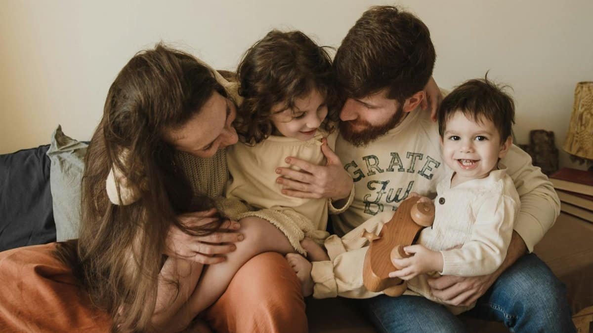 A joyful family moment with parents and children embracing and laughing together indoors.