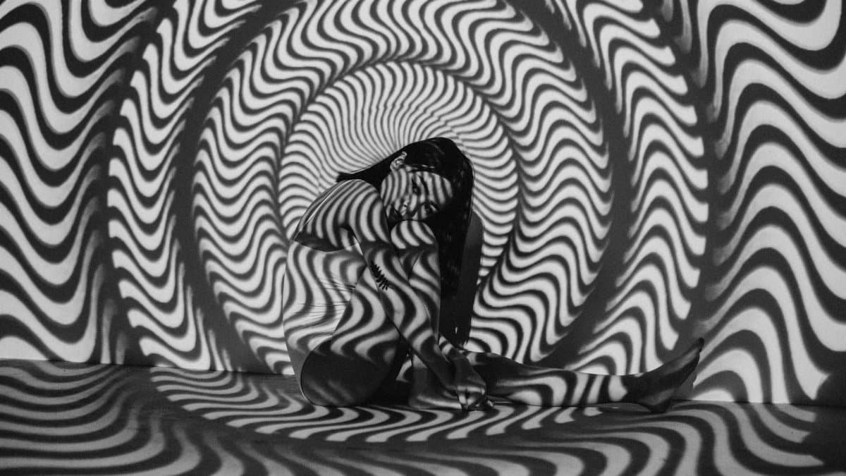 A woman enveloped in a trippy black and white optical illusion, creating a striking visual effect.