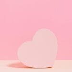 Simple and elegant pink heart shape on a pastel pink background, perfect for Valentine's Day themes.