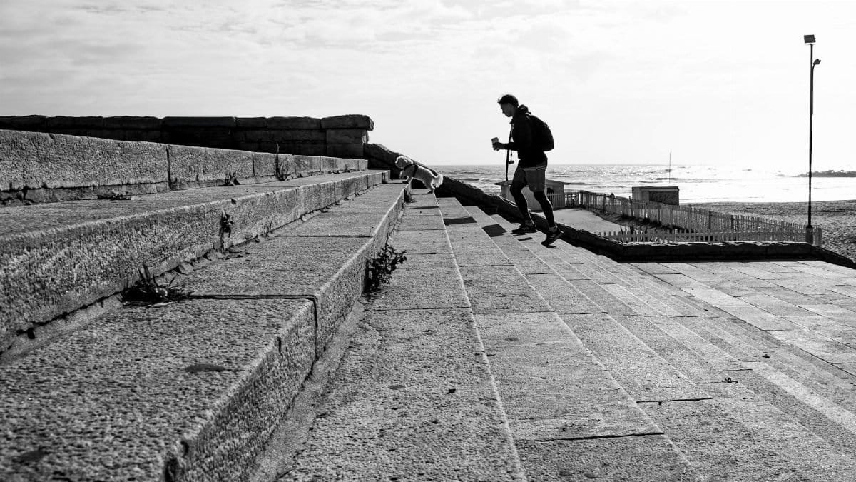 A person walks along seaside steps in a black and white urban photograph from Mar del Plata, Argentina.