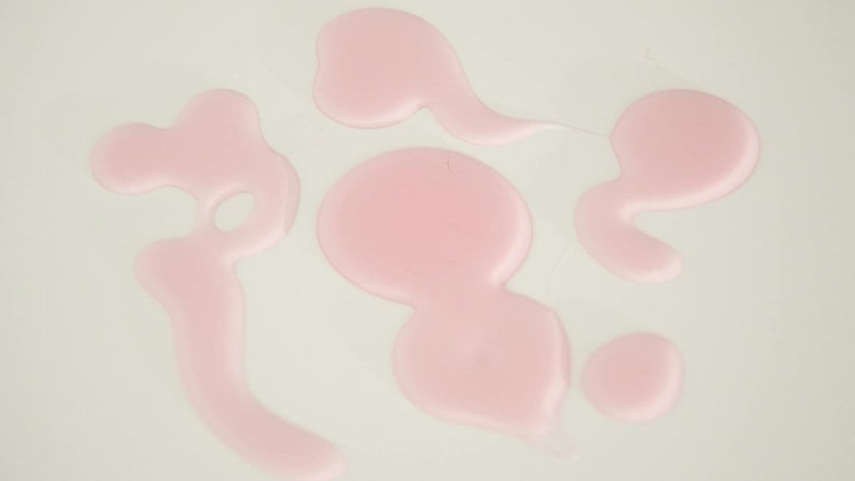 Creative abstract composition of pink liquid droplets on a white backdrop, ideal for backgrounds or artistic elements.