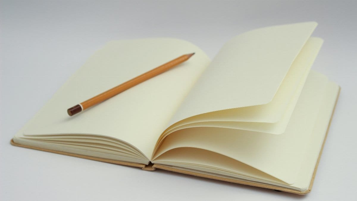 An open notebook with blank pages and a pencil, perfect for starting new ideas or journaling.