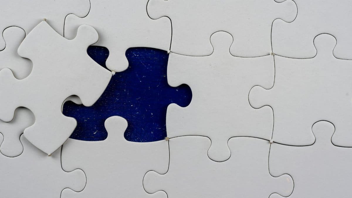An artistic close-up of a puzzle with one missing piece revealing a contrasting background.