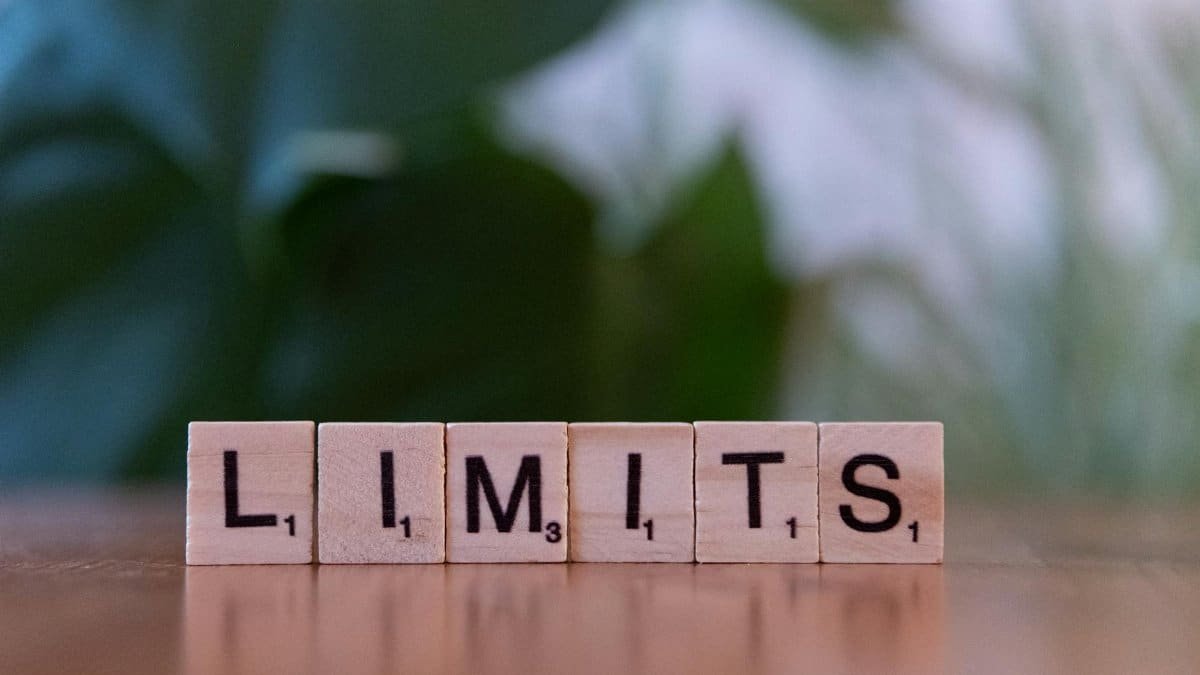 Wooden letter tiles forming the word 'LIMITS' on a wooden table.