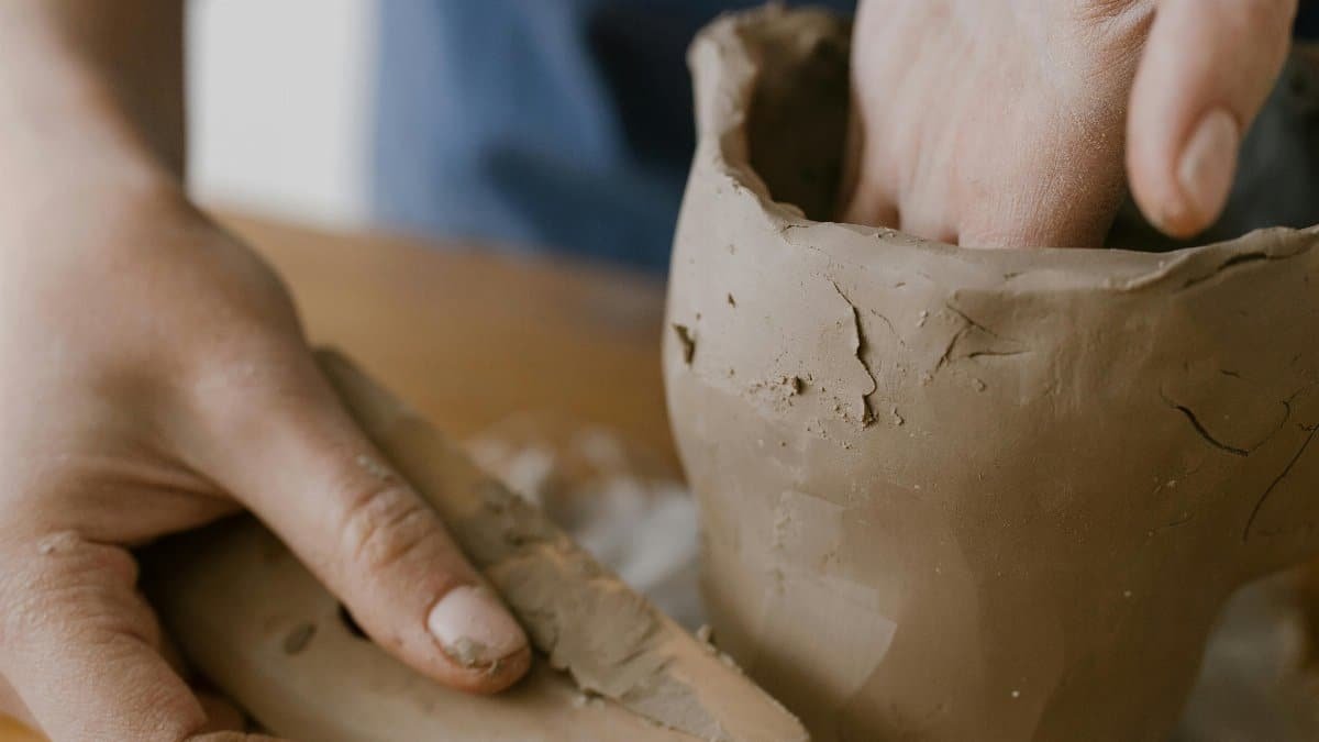 Close-up of hands shaping a clay pot, showcasing the art of pottery making.