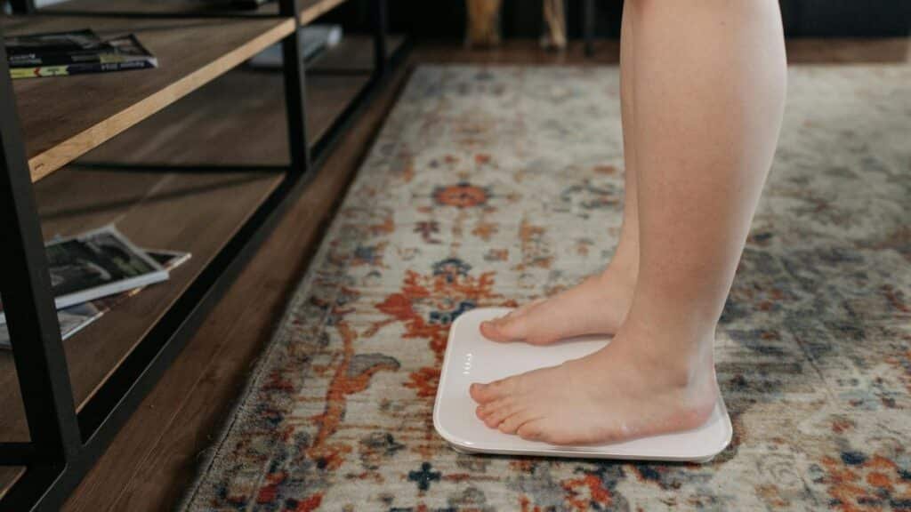 Feet standing on a digital scale in a cozy home setting, health and wellness concept.