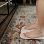 Feet standing on a digital scale in a cozy home setting, health and wellness concept.