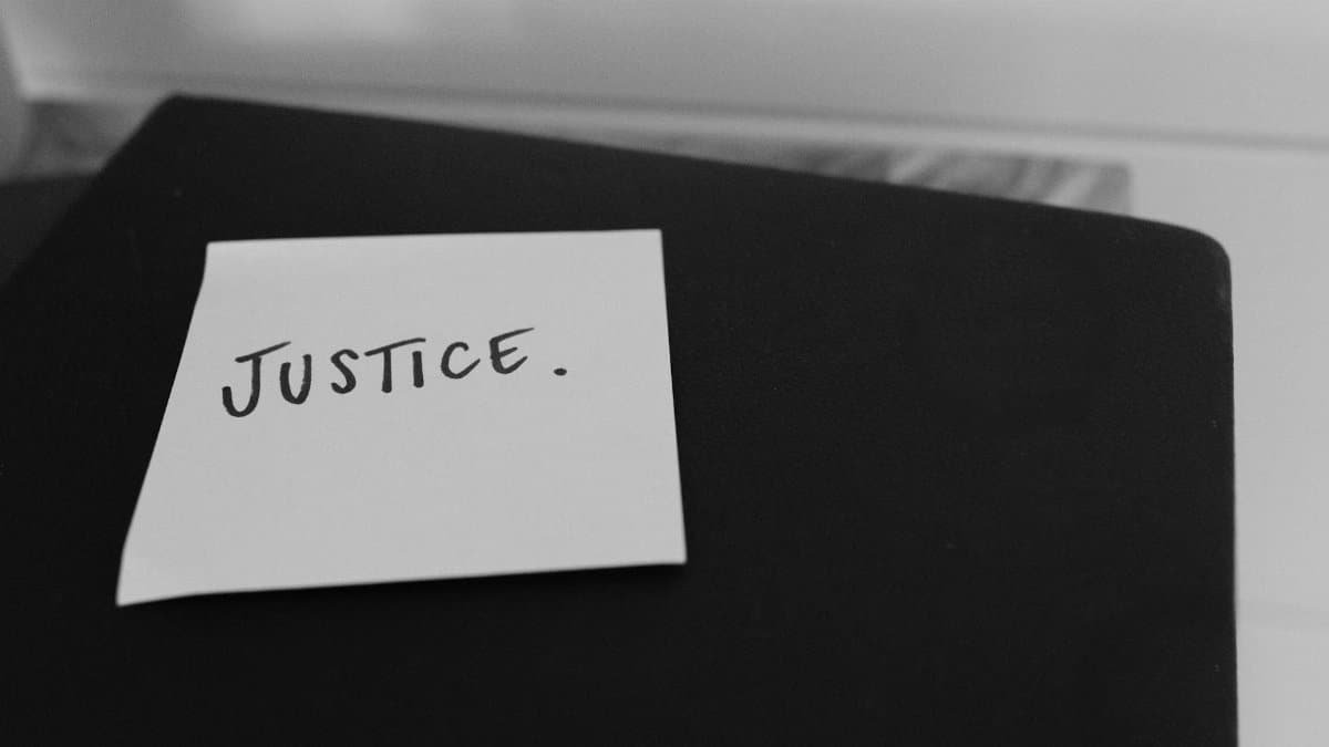Black and white photo of a sticky note with 'Justice' written on it, conveying a powerful message.