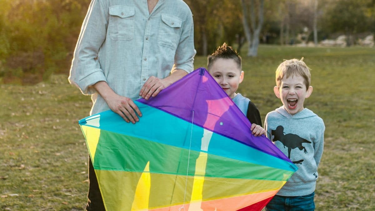 A joyful moment of a family with kids flying a colorful kite outdoors during sunset.