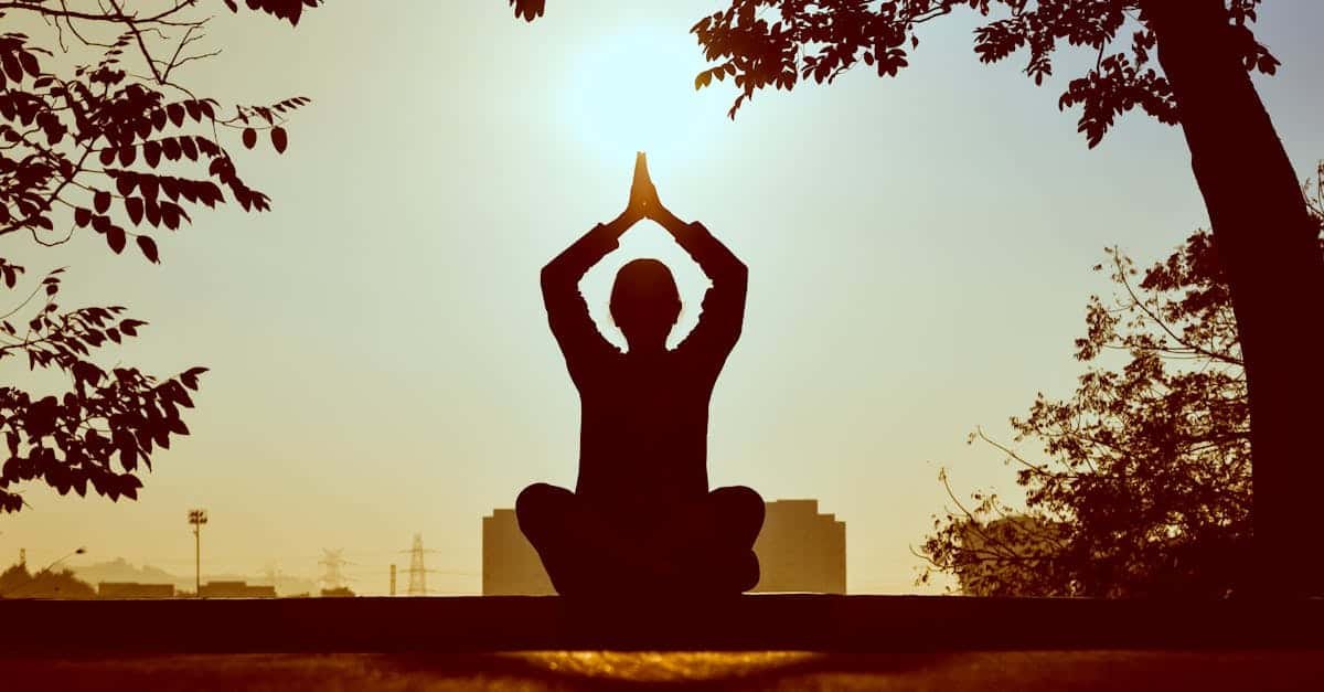Silhouette of a person practicing yoga outdoors during sunrise, creating a calming atmosphere via Pexels